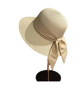 Elegant beige straw sun hat with a wide brim and decorative bow on a display stand