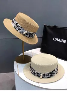 Detailansicht der Strohhüte mit floralen Chiffonbändern und Perlenverzierung