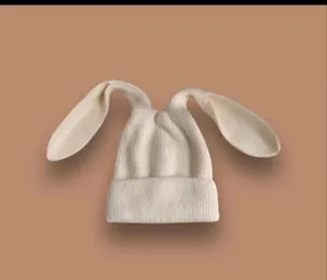 Dettaglio trama di berretto in maglia panna con lunghe orecchie di coniglio morbide