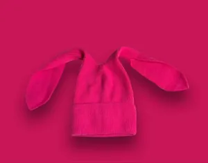 Dettaglio del cappello in maglia rosa acceso con lunghe orecchie da coniglio