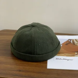 Bonnet docker en velours côtelé vert foncé avec texture côtelée et bouton sur bois