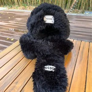 Cute black plush winter hat with long bunny ears and woven label on a wooden table