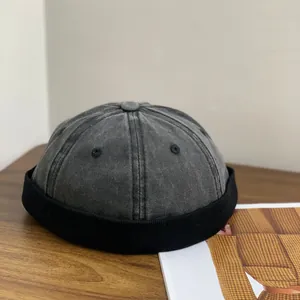 Bonnet docker gris délavé avec bord en velours noir sur un bureau en bois