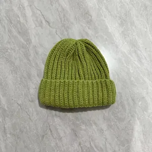 Close-up of grass green knit beanie showing thick ribbed texture and wide folded cuff