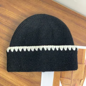 Dettaglio del berretto in maglia nera con bordo all'uncinetto bianco e trama a coste