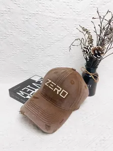 Close-up of distressed brown baseball cap with ZERO embroidery on white textured background
