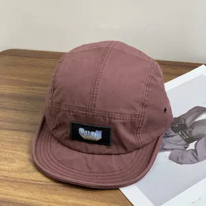 Retro terracotta camper hat with blue GUON patch on a wooden background