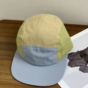 Detail of multi-color five-panel camp cap with breathable eyelets on wooden table