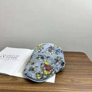 Vintage light blue denim baseball cap with realistic floral print on wooden table