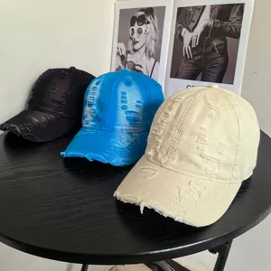 Close-up of distressed baseball caps with ripped details in black, blue, and cream colors