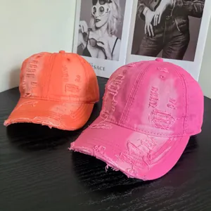Distressed cotton baseball caps in bright orange and rose pink on a stylish wood table