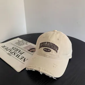 Détail de la visière usée avec bords déchirés sur la casquette de baseball vintage brodée