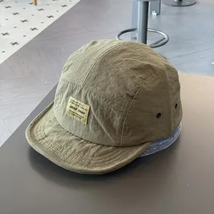 Détail de casquette 5-panel en tissu vert olive à séchage rapide et étiquette tissée