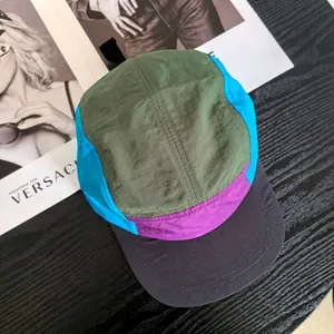 Retro multi-color 5-panel camp hat in olive green and blue on wooden table