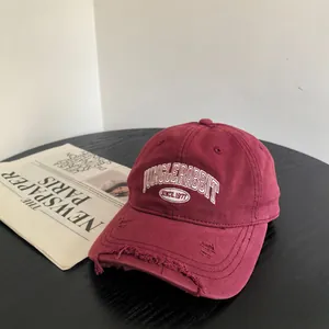 Gros plan de la casquette vintage bordeaux avec broderie et détails usés sur le rebord