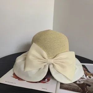 Detail of elegant straw sun hat with large organza bow and wide pleated brim detail