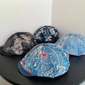 Detail view of four vintage denim floral newsboy caps in different washed blue colors