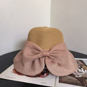 Close-up of a woven straw sun hat featuring a large nude pink organza bow detail