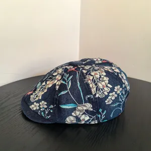 Detail view of American vintage floral denim newsboy cap on a dark wooden table