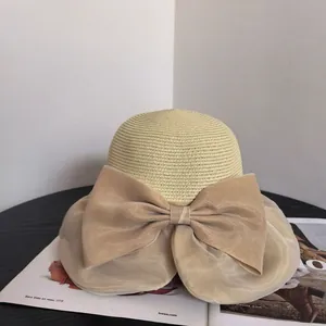 Elegant beige woven straw sun hat with a large organza bow for summer beach vacation