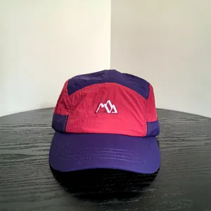 Dettaglio del cappellino outdoor a 5 pannelli con design color-block viola e rosso scuro