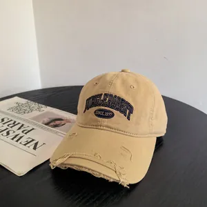 Gros plan sur une casquette vintage kaki avec visière usée et broderie bleu marine