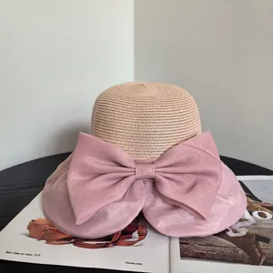 Summer straw sun hat with large pink organza bow and wide brim for beach vacation wear