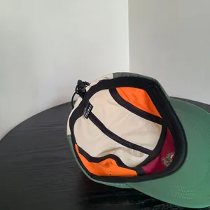 Dettaglio cappello stile montagna color-block con tessuto traspirante e cinturino regolabile