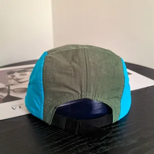 Adjustable nylon webbing strap and plastic buckle on a five-panel color-block sports cap