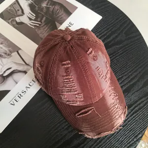 Close-up of distressed cotton baseball cap in brown featuring vintage ripped hole details