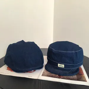 Détails de casquettes en denim bleu foncé avec surpiqûres blanches et étiquette textile