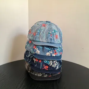 Close-up of floral print denim newsboy caps in various colors on a wooden table