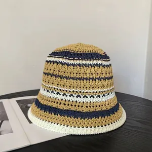 Detailed close-up of a striped hollow knit bucket hat on a wooden desk setting