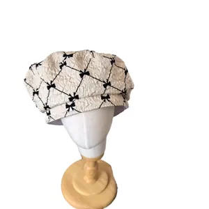 Women's seersucker beret with black bow accents and classic plaid pattern on white
