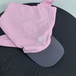 Detail of pink sun hat with grey brim and Nice patch on a textured wooden table