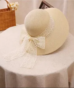 Detail of summer straw hat featuring delicate beige weave and large white lace bow