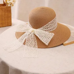Straw sun hat with wide brim and white lace bow decoration for beach vacations