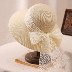 Detail of beige straw sun hat with large white lace bow on a vintage wooden stand