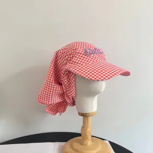 Dettaglio cappello parasole a quadretti rossi con ricamo Freedom e protezione per il collo