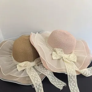 Detail of woven straw sun hats with elegant organza brim and large lace bow ties