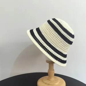 Cappello estivo in paglia a righe a tesa larga per donna su supporto in legno