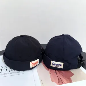 Unisex brimless docker cap in black and navy blue with embroidered camping label