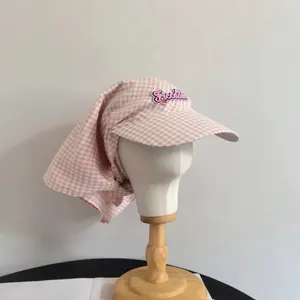 Dettaglio del cappello da sole a quadretti rosa con ricamo Freedom e protezione nuca