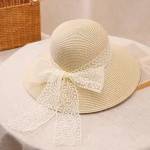 Women's wide brim straw sun hat with white lace bow on a decorative table setting