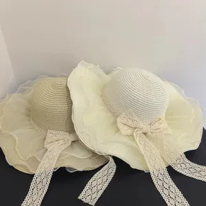 Detailed view of women's straw sun hat featuring wavy organza brim and lace bow ribbons