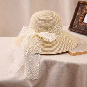 Straw sun hat with white lace bow on burlap table with vintage books and frame
