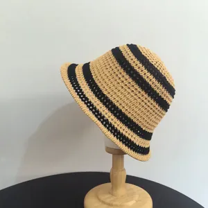 Dettaglio della trama del cappello da sole in paglia a righe nere su espositore di legno