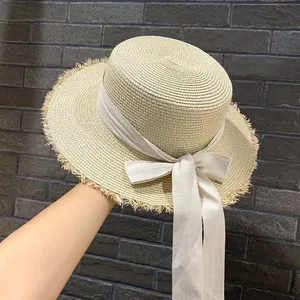 Cappello di paglia a tesa sfrangiata con fiocco in nastro crema per vacanze estive