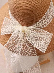 Detailed view of hand-woven straw hat featuring an elegant beige lace bow decoration