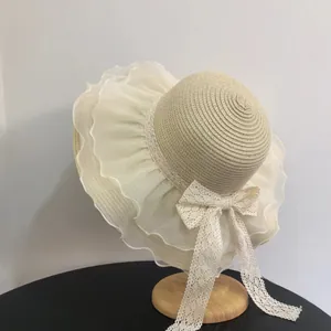 Straw sun hat with white organza wavy brim and delicate lace bow for summer travel